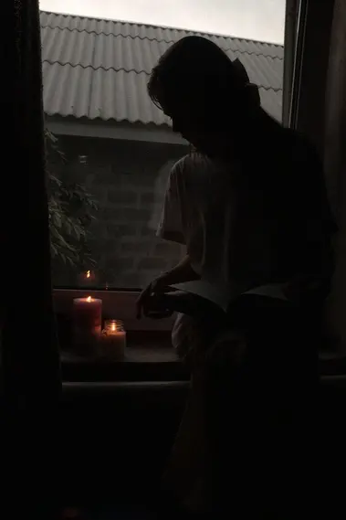 a woman sitting on a window sill reading a book